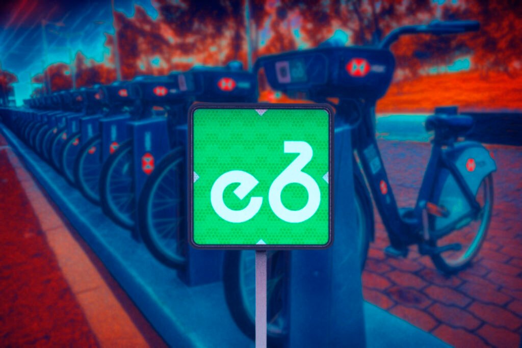 Señal de Ecobici de movilidad integrada en color verde, colocada junto a un punto de bicicletas compartidas en la CDMX. Marca el acceso al sistema de transporte urbano en bici.  Parte de las Señales de movilidad integrada.